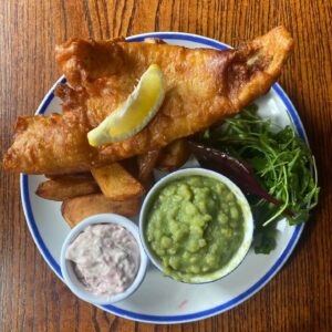 Individual plate of golden-battered fish and hand-cut chips, presented as a classic choice in this January food offer.